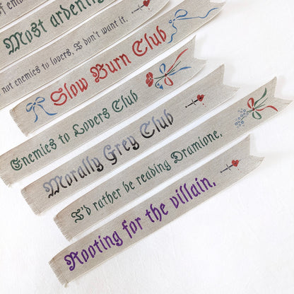 Hand painted linen ribbon bookmarks that read "Sugar, spice, and everything nice" "Slow Burn Club" "Enemies to Lovers Club" and more phrases