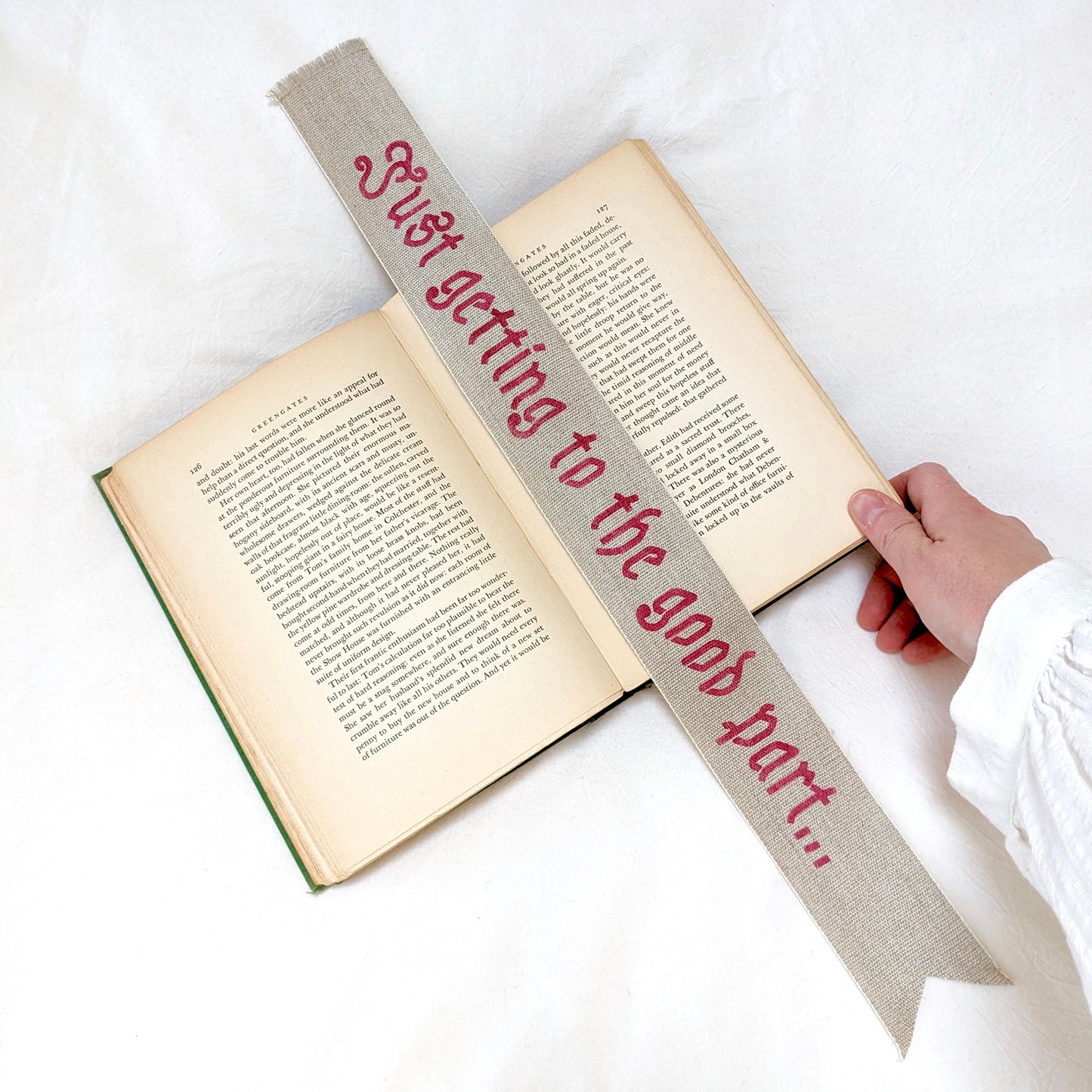 A hand painted linen ribbon bookmark that reads "Just getting to the good part..."