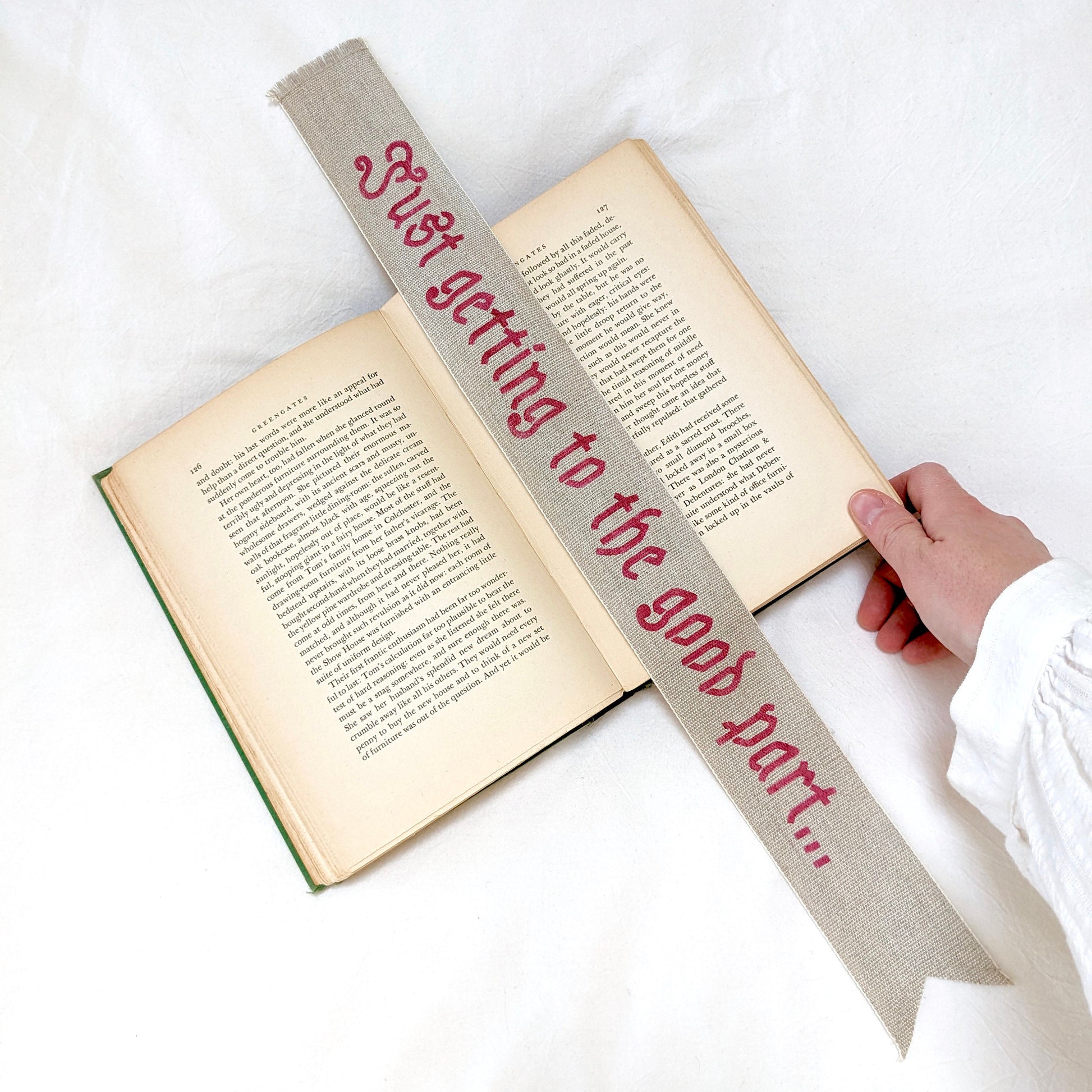 A hand painted linen ribbon bookmark that reads "Just getting to the good part..."