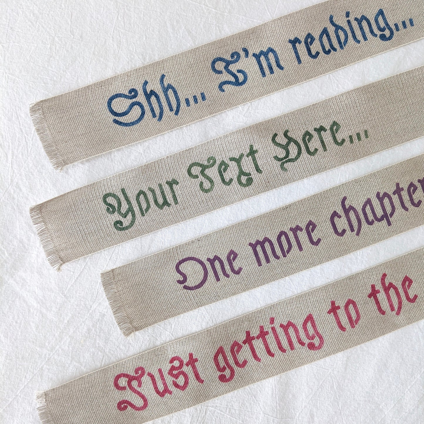 A hand painted linen ribbon bookmark that reads "Shh... I'm reading..." "Just getting to the good part..." or "One more chapter..."
