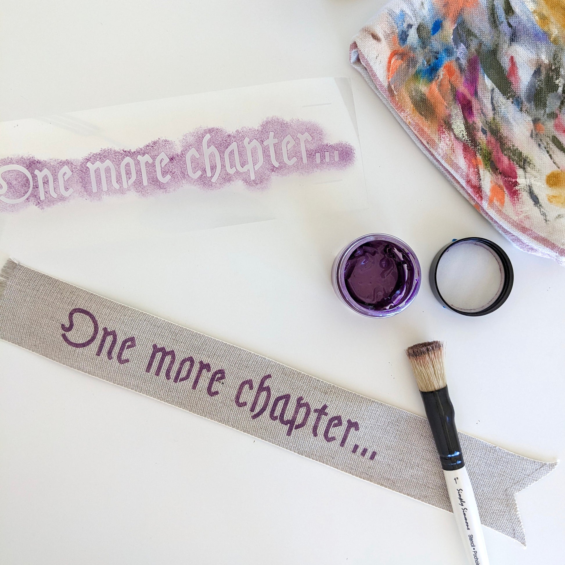 A hand painted linen ribbon bookmark that reads "One more chapter..."
