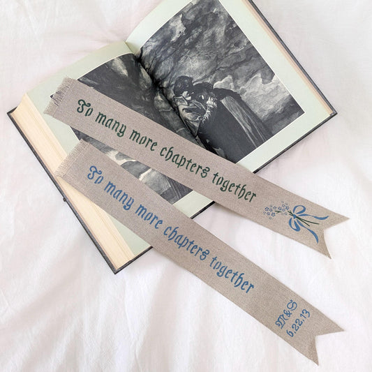 Hand painted linen ribbon bookmark that reads "To many more chapters together" with either initials and wedding anniversary date motif or forget-me-not-flower motif
