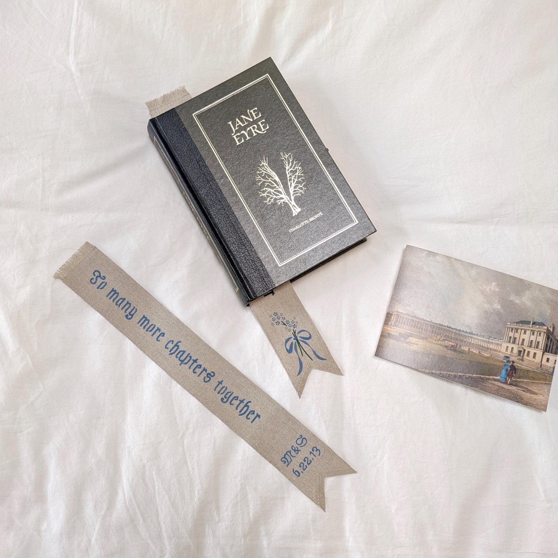 Hand painted linen ribbon bookmark that reads "To many more chapters together" with initials and wedding anniversary date motif